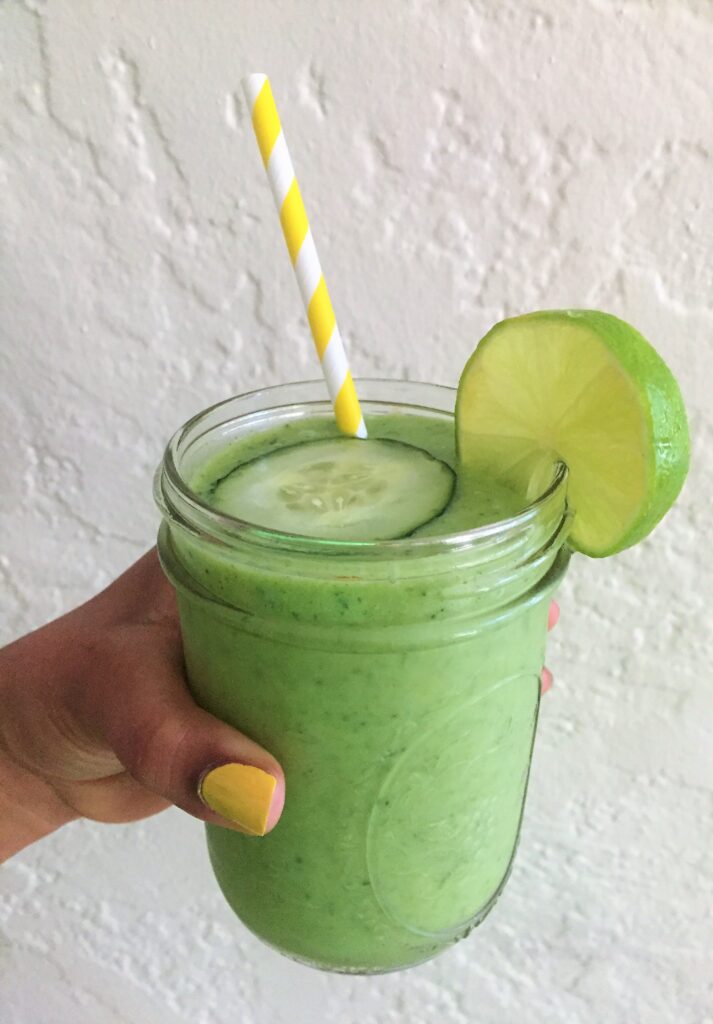 Hand holding Creamy Tropical Cucumber Smoothie courtesy of Vegan Fit Carter