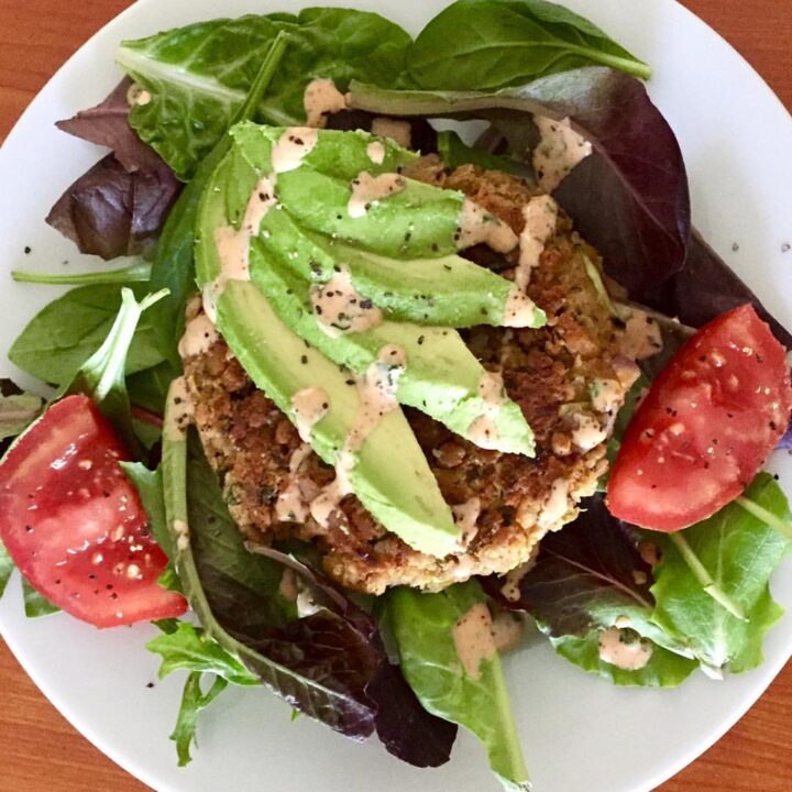 Salad topped with Chickpea Veggie Patty, drizzled with Chipotle Lime Sauce.